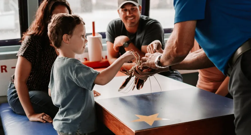 Family at a restaurant inspecting a lobster